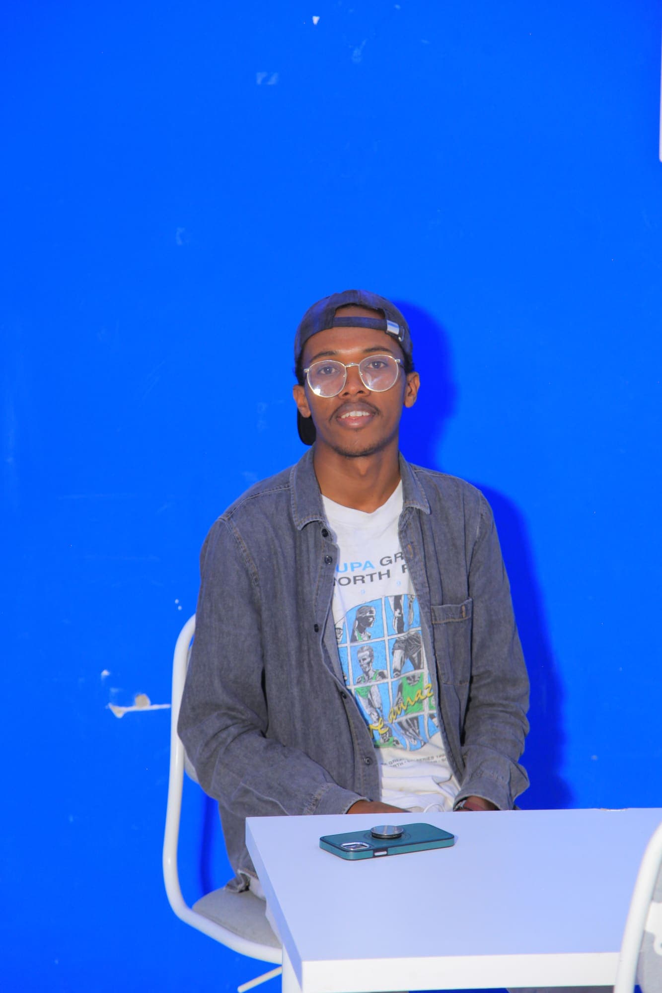 A community member seated at a white table against a blue wall