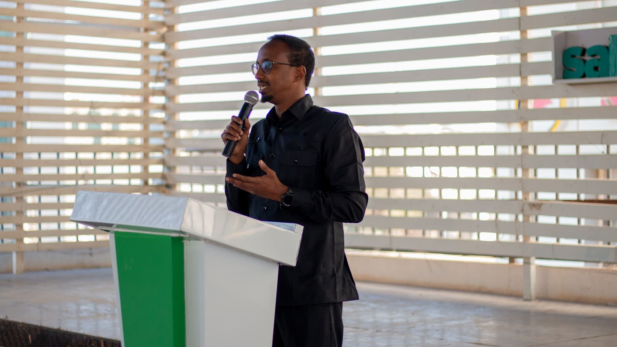 A speaker holding a microphone talks from the podium