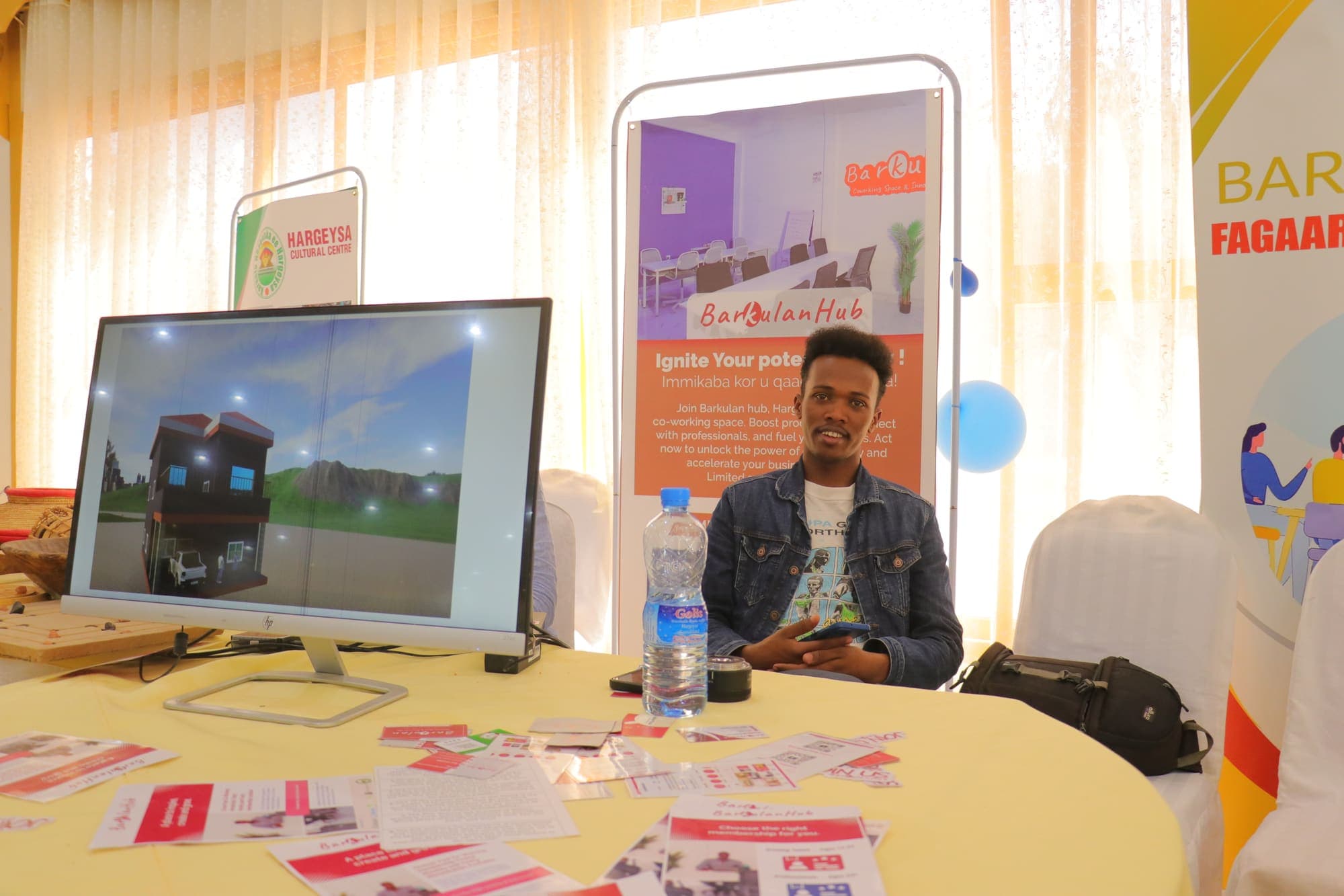 An exhibition table with a screen, leaflets and a BarkulanHub banner