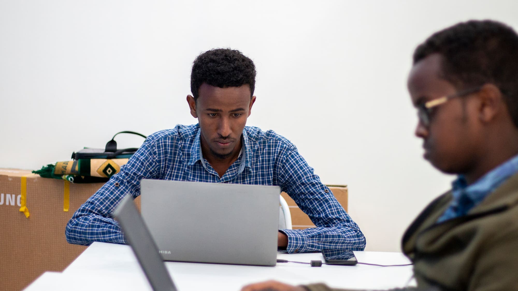 A man works at a laptop at a shared table